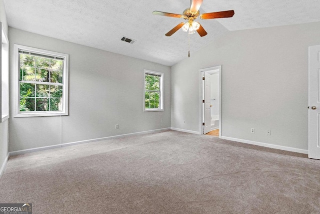 carpeted spare room with ceiling fan, a textured ceiling, lofted ceiling, and a wealth of natural light