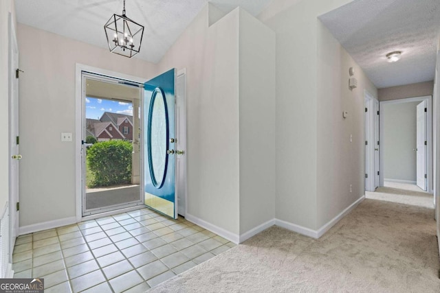 carpeted entryway with a chandelier and a textured ceiling