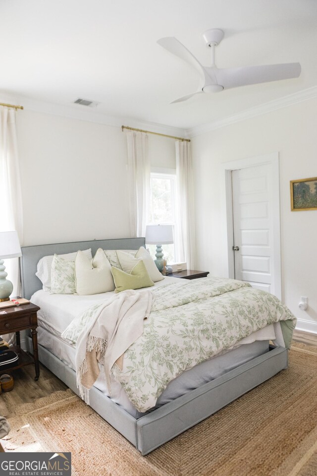 bedroom with ceiling fan, hardwood / wood-style floors, and ornamental molding