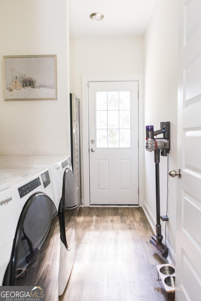 laundry room with independent washer and dryer and light hardwood / wood-style flooring