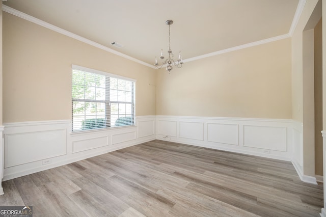 spare room featuring a chandelier, light hardwood / wood-style floors, and crown molding