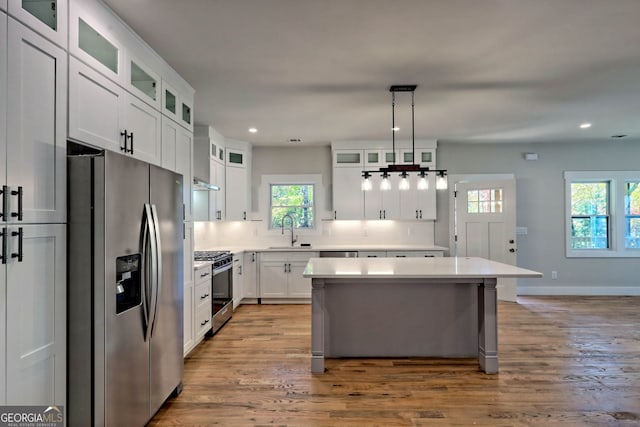 kitchen featuring appliances with stainless steel finishes, a kitchen island, sink, light hardwood / wood-style floors, and white cabinetry