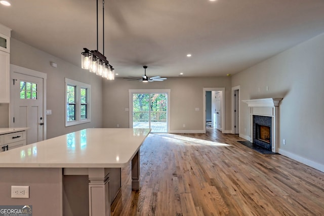 kitchen featuring plenty of natural light, white cabinets, hanging light fixtures, and light wood-type flooring