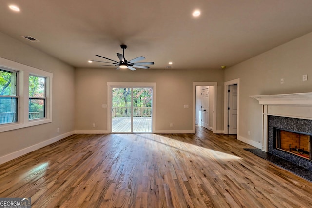 unfurnished living room featuring ceiling fan, light hardwood / wood-style flooring, plenty of natural light, and a premium fireplace