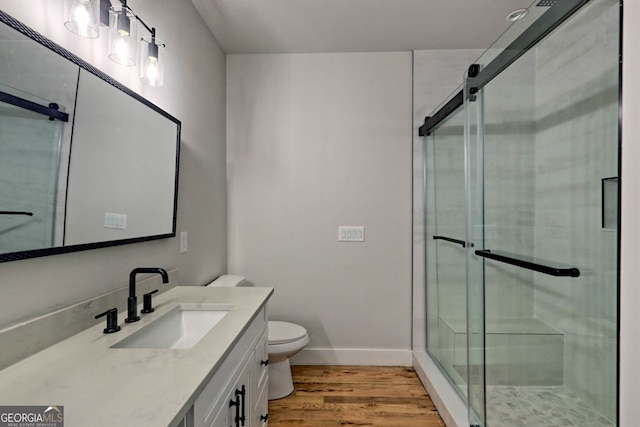 bathroom with wood-type flooring, vanity, toilet, and a shower with shower door