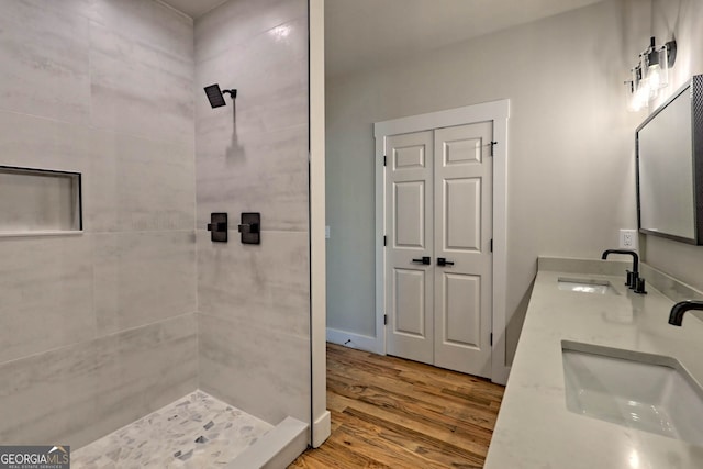 bathroom with hardwood / wood-style flooring, vanity, and tiled shower