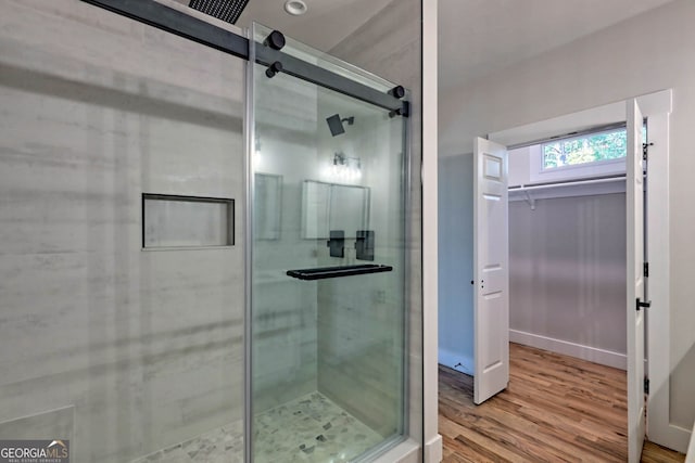 bathroom with wood-type flooring and a shower with shower door