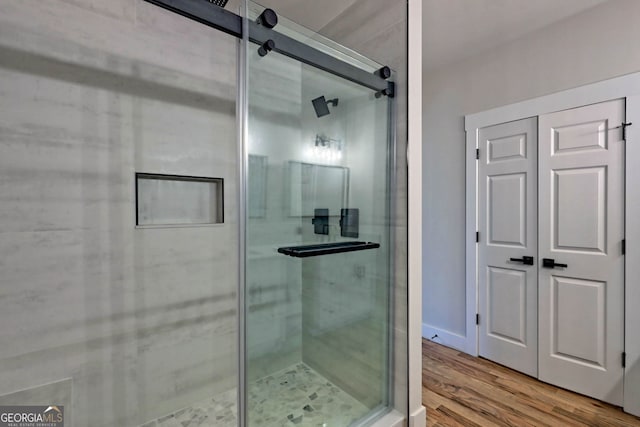 bathroom with a shower with shower door and hardwood / wood-style flooring