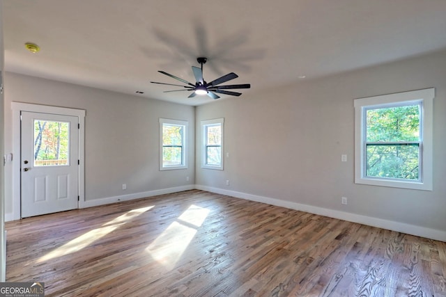 empty room with ceiling fan, a healthy amount of sunlight, and light wood-type flooring