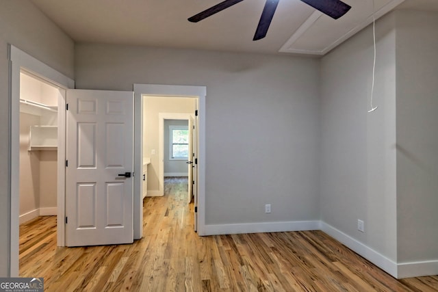 unfurnished bedroom with ceiling fan, a closet, a walk in closet, and light hardwood / wood-style flooring