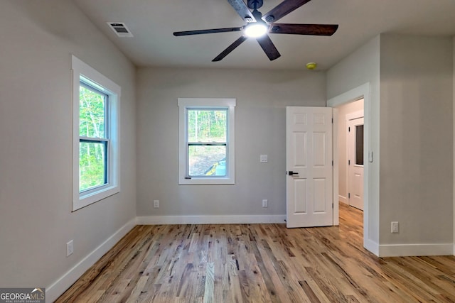 unfurnished bedroom with multiple windows, ceiling fan, and light wood-type flooring