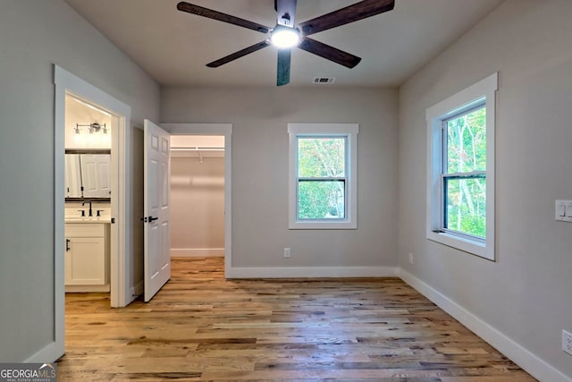 unfurnished bedroom with connected bathroom, ceiling fan, sink, and light hardwood / wood-style floors