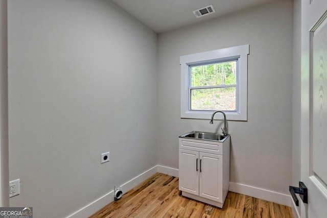 laundry area with hookup for an electric dryer, cabinets, sink, and light hardwood / wood-style flooring