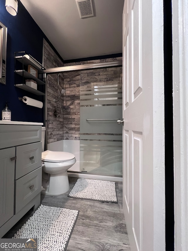 bathroom featuring vanity, hardwood / wood-style floors, toilet, and an enclosed shower