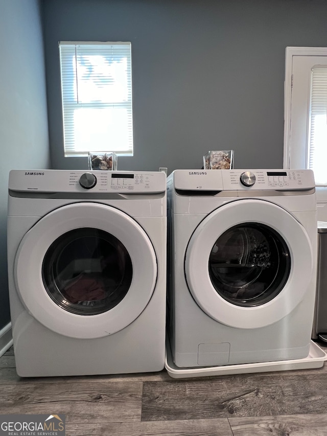 laundry area with a healthy amount of sunlight, wood-type flooring, and washer and dryer