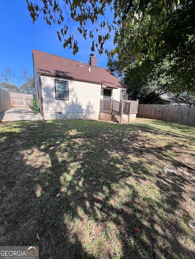 back of property featuring a lawn and a deck