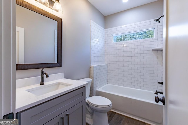 full bathroom with tiled shower / bath combo, vanity, toilet, and hardwood / wood-style floors