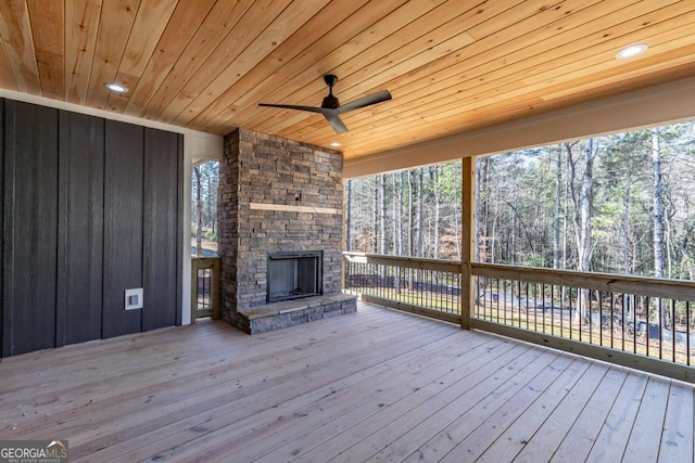 wooden deck featuring ceiling fan and an outdoor stone fireplace