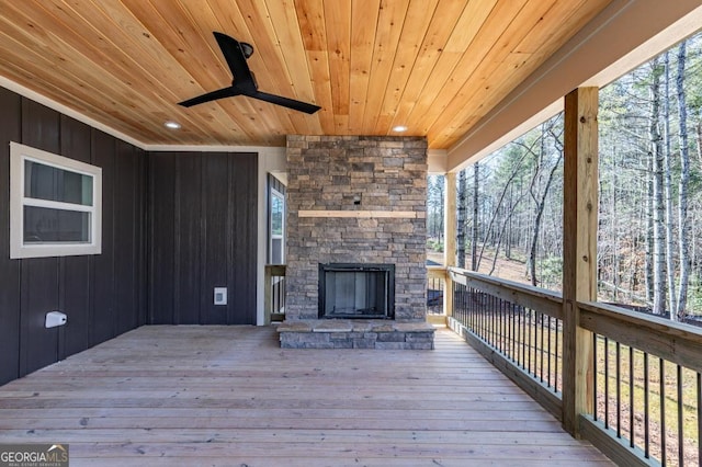 wooden deck with ceiling fan and an outdoor stone fireplace