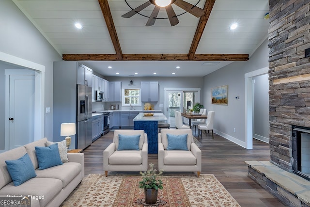 living room featuring hardwood / wood-style floors, sink, beamed ceiling, ceiling fan, and a fireplace