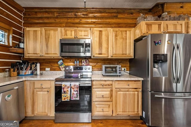 kitchen featuring light brown cabinetry, stainless steel appliances, and light hardwood / wood-style floors