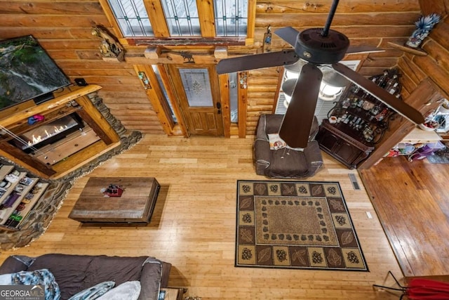 living room featuring hardwood / wood-style floors, ceiling fan, and rustic walls