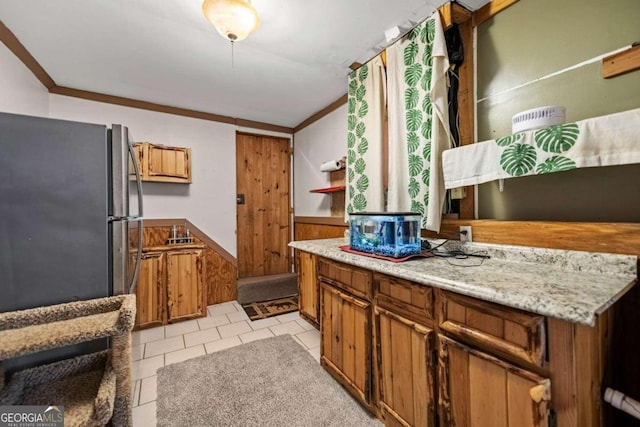 kitchen with stainless steel refrigerator, wooden walls, crown molding, and light tile patterned flooring