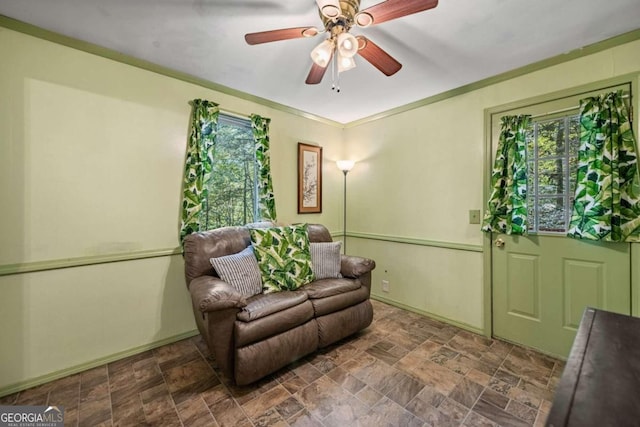 sitting room featuring ceiling fan, ornamental molding, and a healthy amount of sunlight