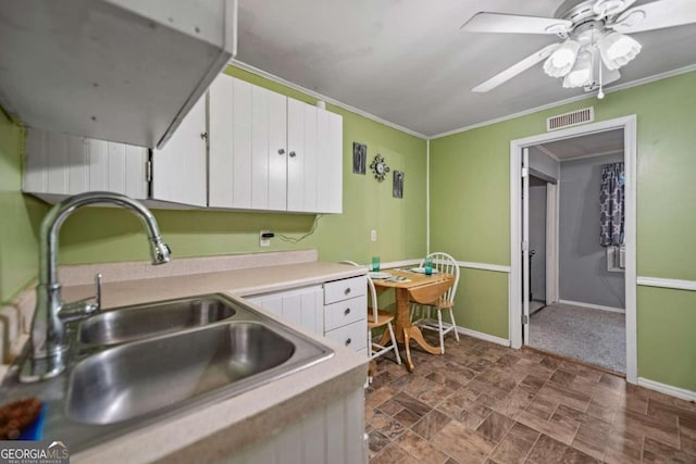 kitchen with ceiling fan, white cabinets, ornamental molding, and sink