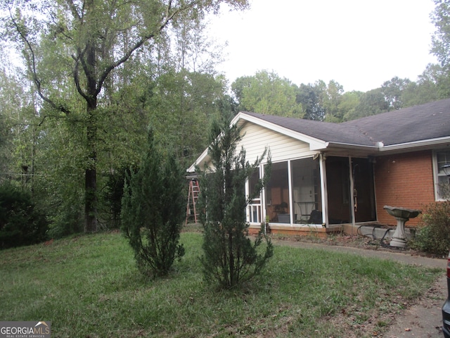 view of side of home featuring a sunroom and a lawn