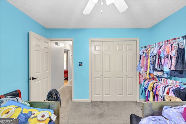 carpeted bedroom with a closet, ceiling fan, and a textured ceiling