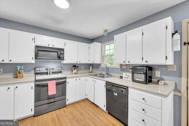 kitchen with a textured ceiling, light hardwood / wood-style floors, sink, white cabinetry, and black appliances