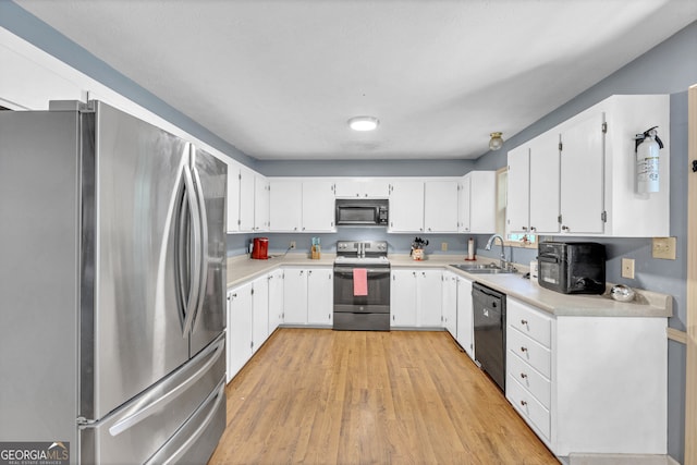 kitchen with black appliances, light hardwood / wood-style floors, white cabinetry, and sink