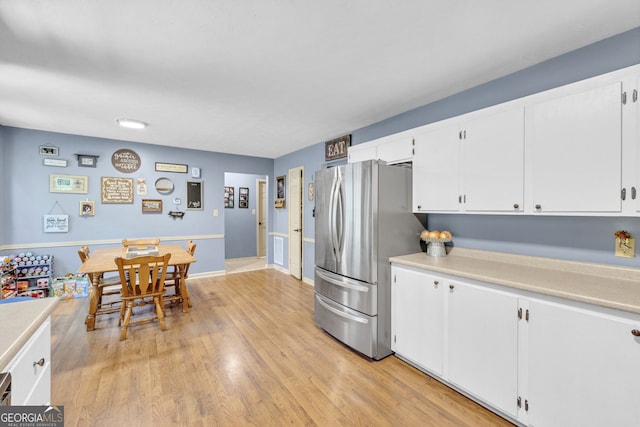 kitchen featuring stainless steel refrigerator, white cabinetry, and light hardwood / wood-style flooring