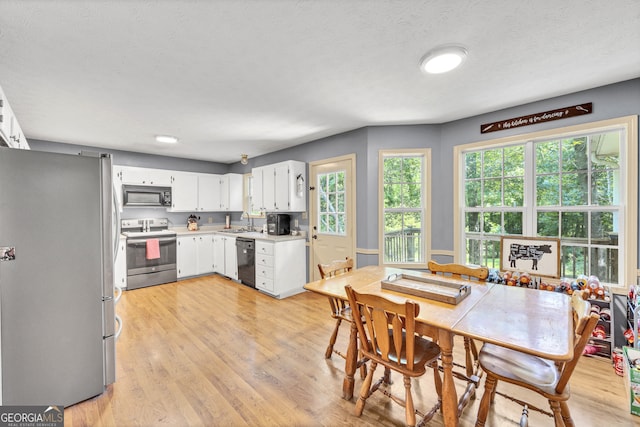 kitchen featuring sink, a textured ceiling, light hardwood / wood-style flooring, white cabinetry, and black appliances