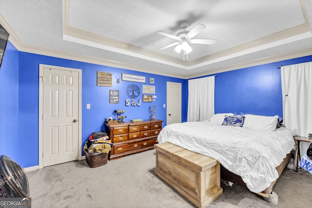 bedroom with a textured ceiling, crown molding, carpet flooring, a tray ceiling, and ceiling fan