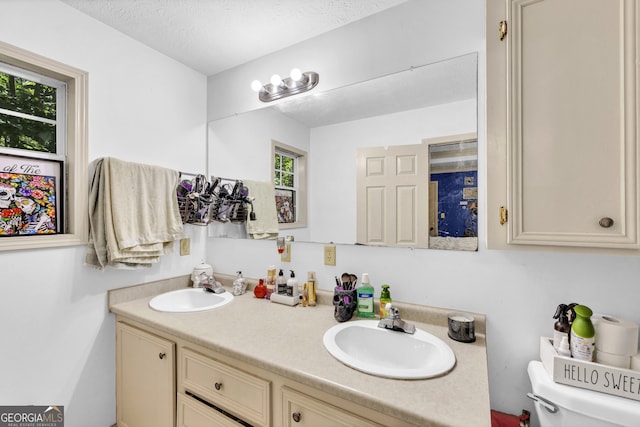 bathroom with a textured ceiling, vanity, and toilet