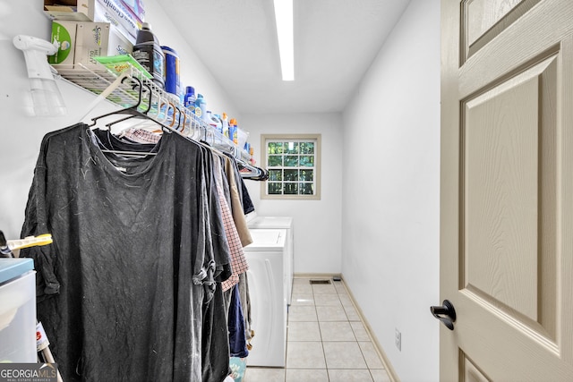 clothes washing area with light tile patterned floors and washer and clothes dryer