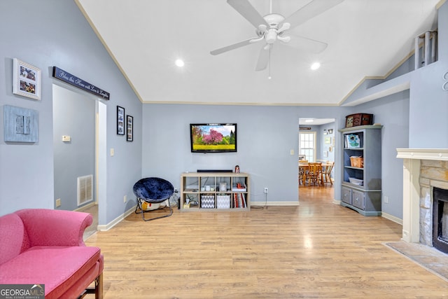 sitting room with light wood-type flooring, a fireplace, ceiling fan, and high vaulted ceiling