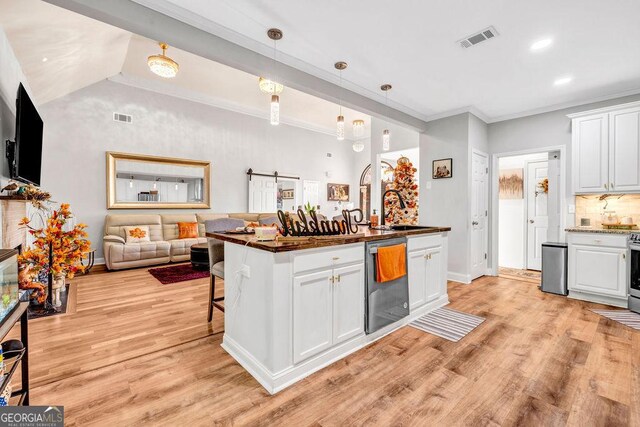 kitchen featuring white cabinets, stainless steel appliances, a barn door, and light hardwood / wood-style flooring