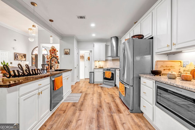 kitchen featuring stainless steel appliances, sink, wall chimney range hood, and white cabinetry