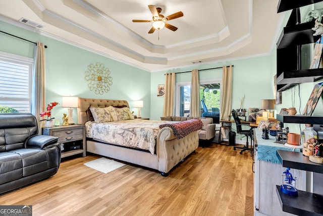 bedroom featuring ceiling fan, ornamental molding, light hardwood / wood-style flooring, and a raised ceiling