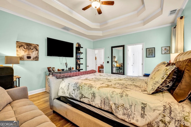 bedroom with a raised ceiling, ornamental molding, hardwood / wood-style flooring, and ceiling fan