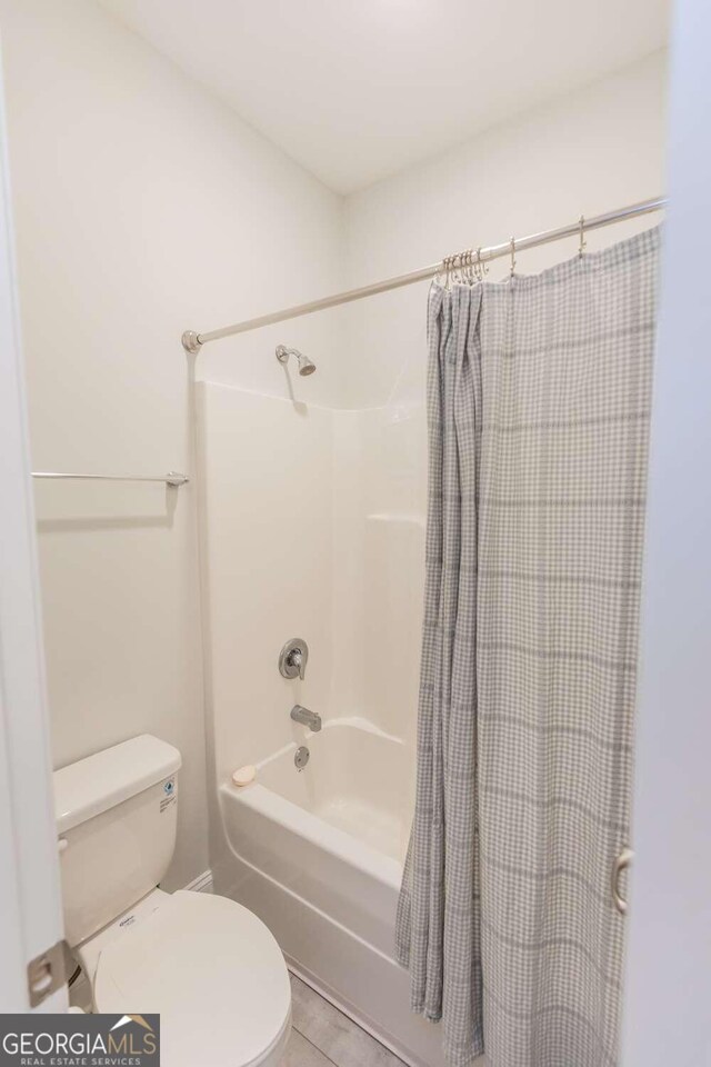 bathroom with tile patterned flooring, toilet, and shower / tub combo with curtain