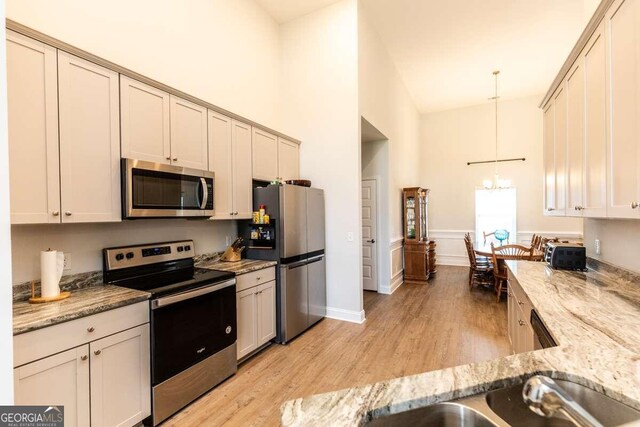 kitchen featuring appliances with stainless steel finishes, hanging light fixtures, light wood-type flooring, and cream cabinetry