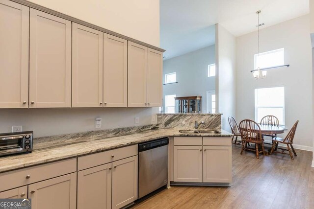 kitchen with light hardwood / wood-style floors, kitchen peninsula, dishwasher, decorative light fixtures, and sink