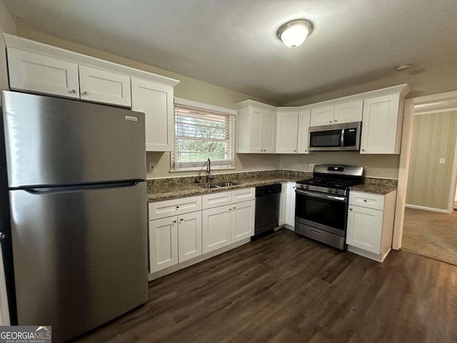 kitchen with dark hardwood / wood-style floors, sink, white cabinets, appliances with stainless steel finishes, and dark stone countertops