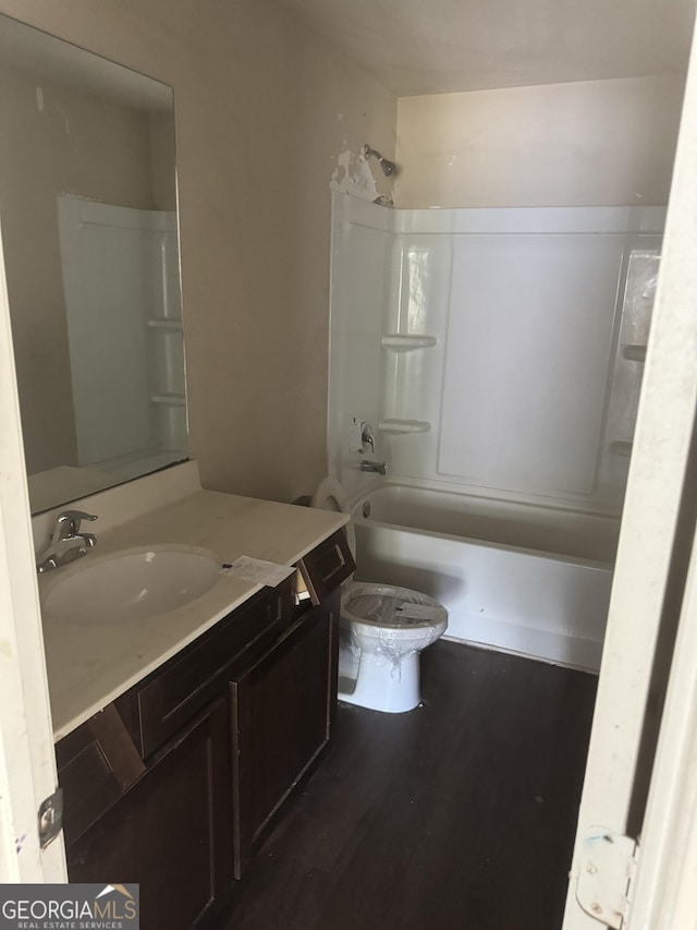 bathroom featuring toilet, bathing tub / shower combination, wood finished floors, and vanity