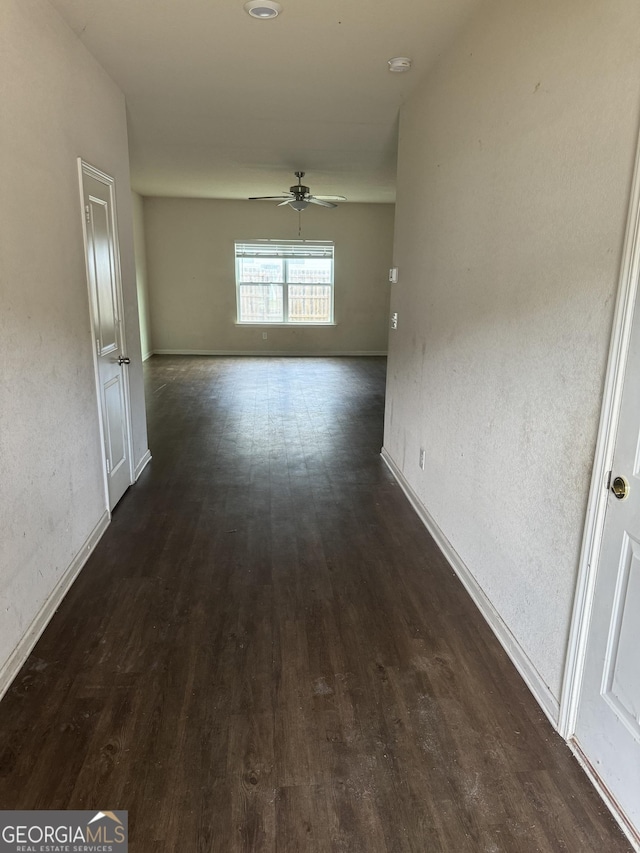 corridor featuring dark wood-style flooring and baseboards