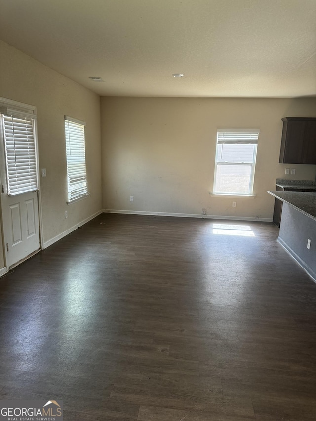 unfurnished living room with baseboards and dark wood-style flooring